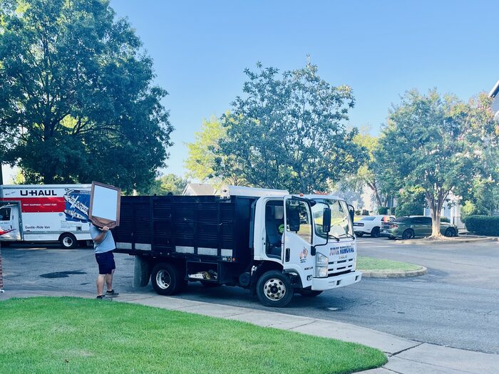 A crew member carrying a box out to the truck on a residential street