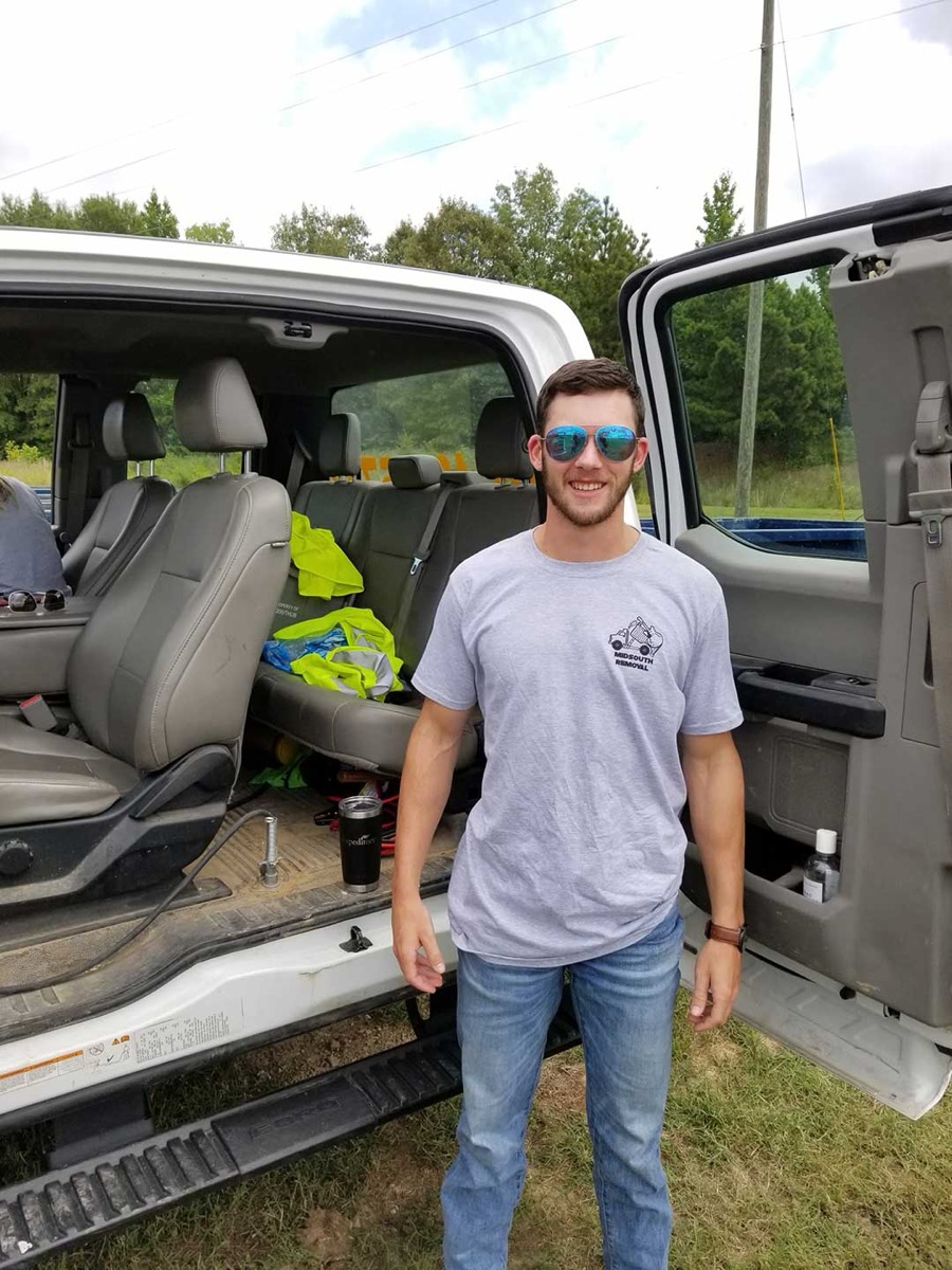 A MidSouth Removal crew member standing at the open door of the truck