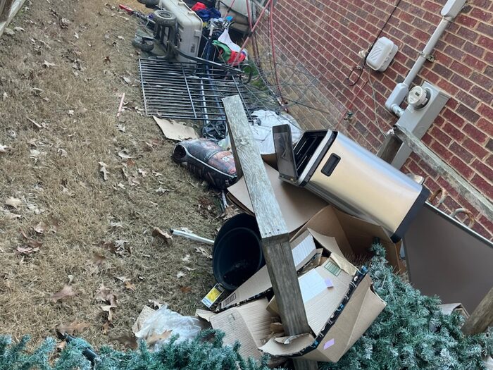 Appliances, a mattress and an artificial tree stacked along the side of a house
