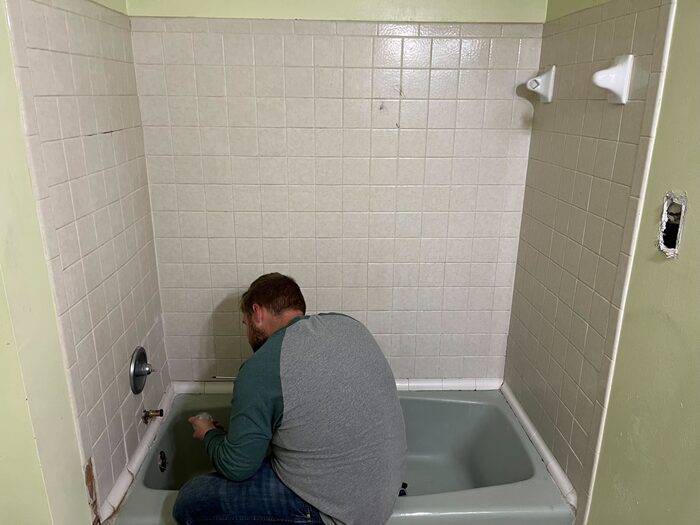 A crew member disconnecting a bathtub during a bathroom strip-out