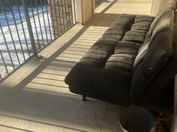 Two futon sofas left out on an apartment balcony