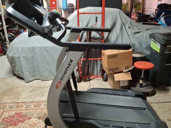 A garage filled with exercise equipment, boxes and stored clutter