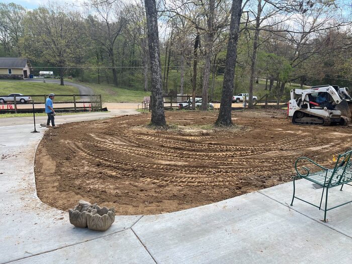 A freshly graded dirt pad beside a paved patio