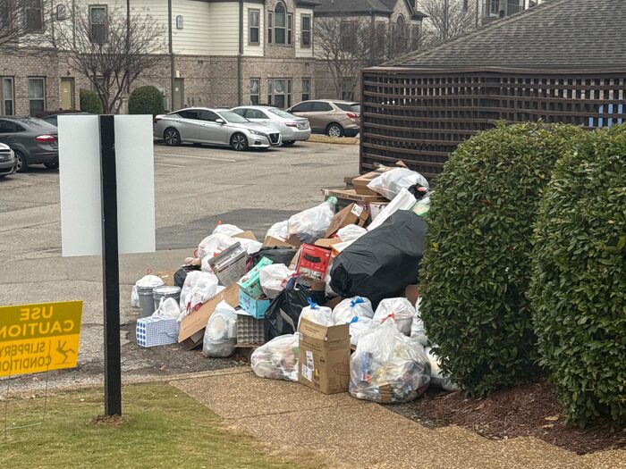 Overflow waste heaped beside the parking area of an apartment complex