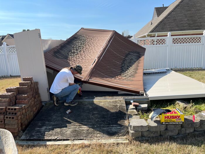 A crew member stripping the roof off a shed during a removal