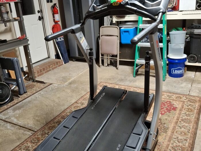 A treadmill standing in an open garage waiting to be collected