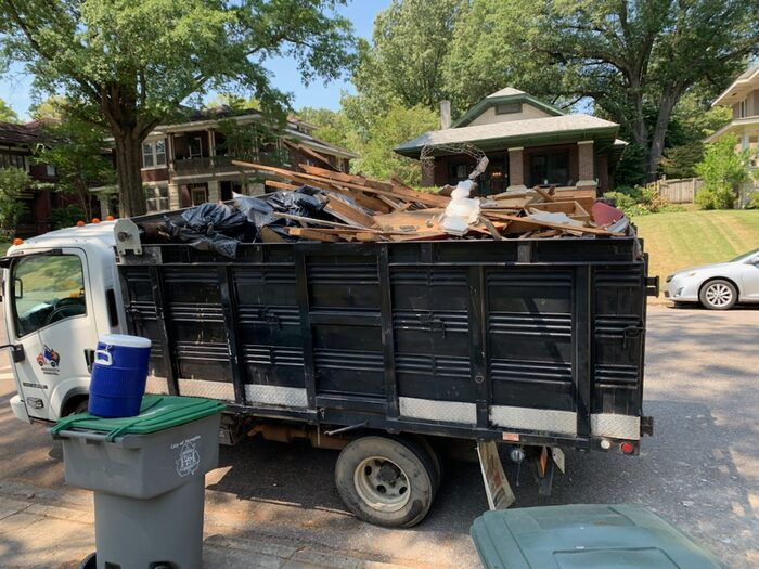 A truck bed heaped with construction debris outside an apartment building