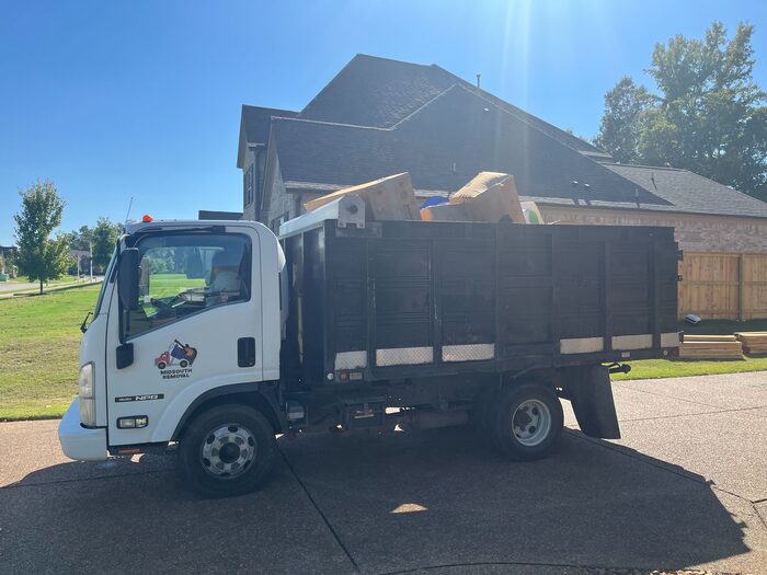 A truck loaded with flattened cardboard and household waste on a driveway