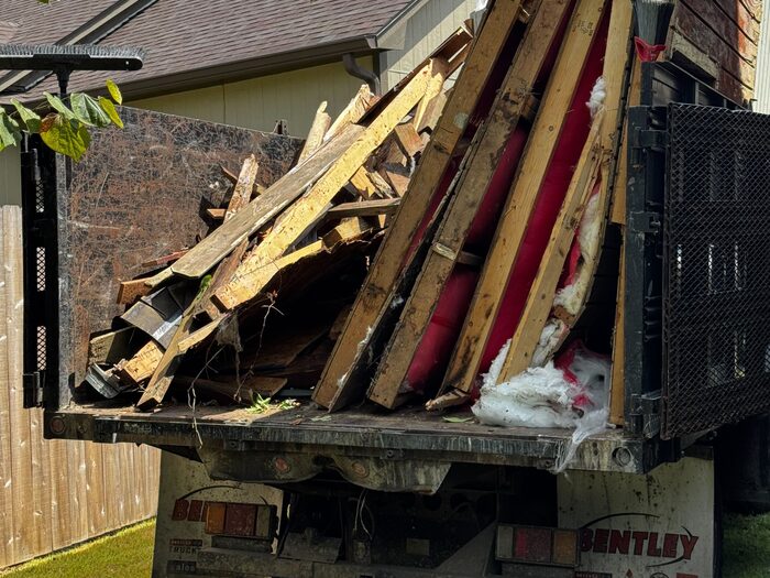 A truck bed loaded with dismantled fence panels and timber